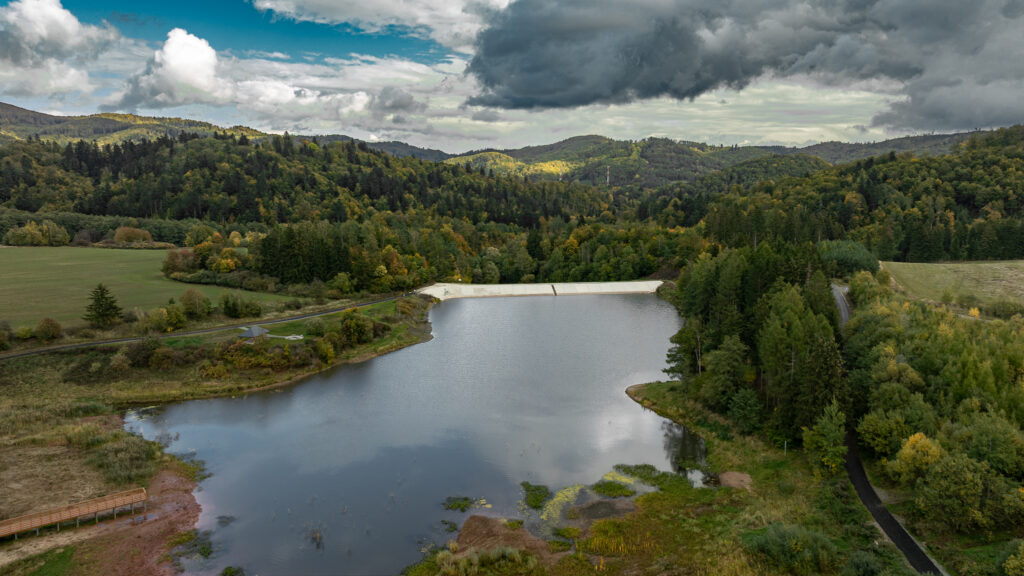 Niewielki staw otoczony gęstymi drzewami sfotografowany z góry.