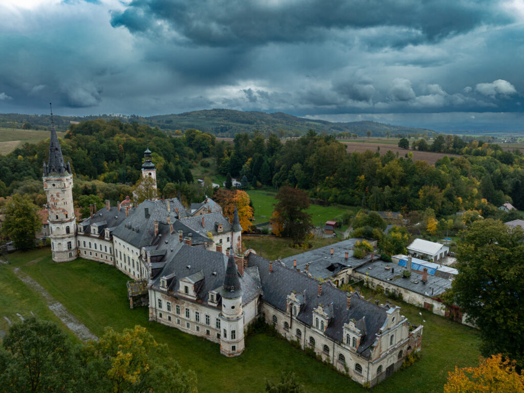 Widok z góry na zabudowania historycznej posiadłości i jej dziedziniec.